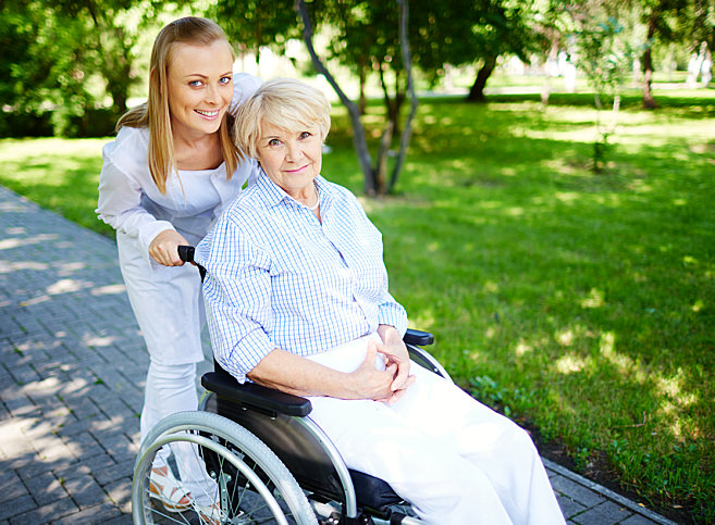 caregiver smiling with her senior patient on a wheelchair